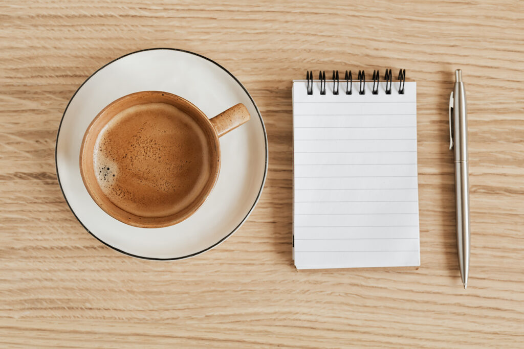 Coffee and a paper notebook with pen