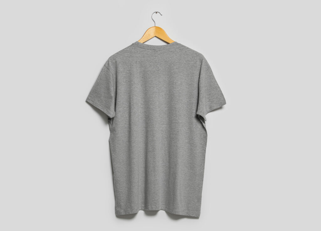 Hanger with grey t-shirt on light wall. Mockup for design