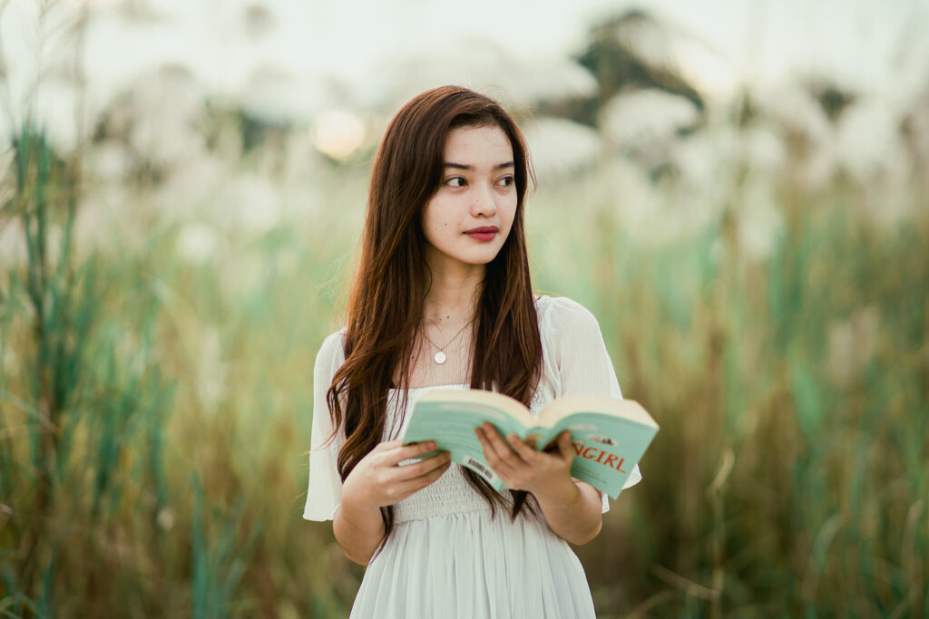 Young Woman in a meadow with a book